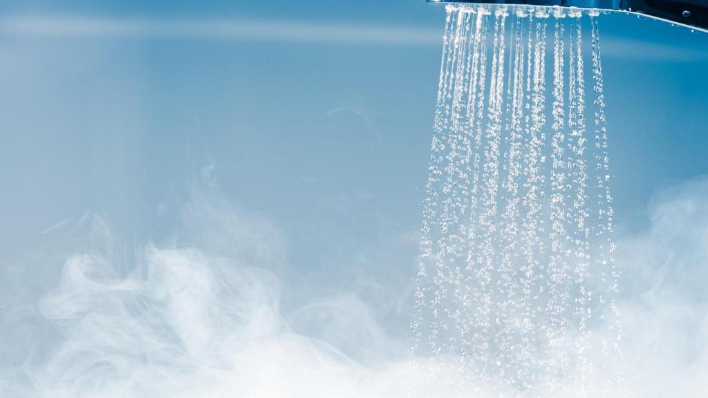 File image of a shower with hot water and steam.