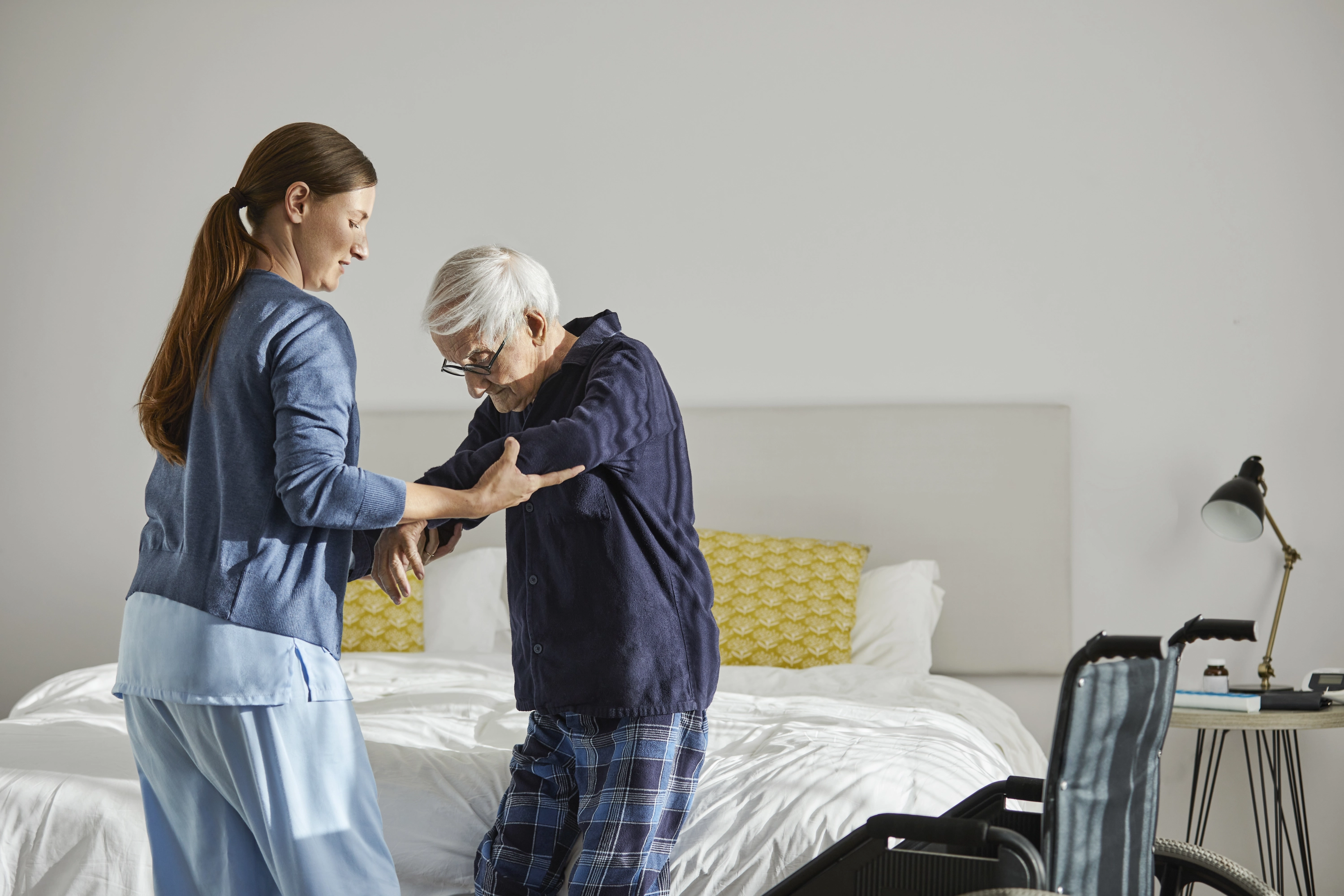 A nursing assistant helps an elderly man with a disability