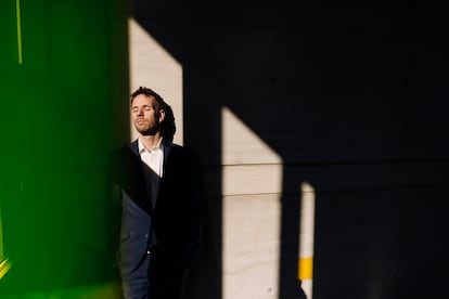 Businessman with closed eyes leaning against a concrete wall