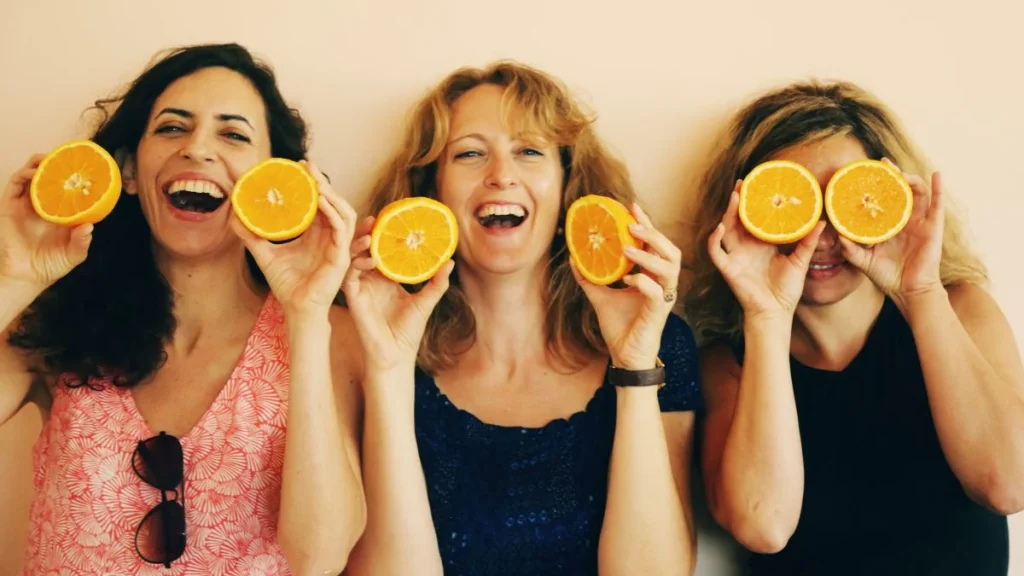 Mujeres sonrientes sosteniendo medias naranjas